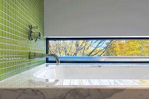 designer bathroom with green wall tiles and large window