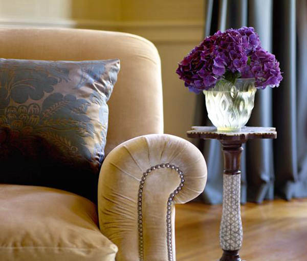 blue pillow and side table with vase with purple flowers