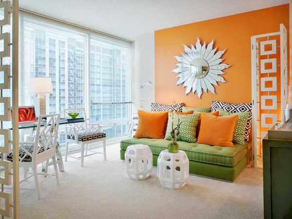 orange wall paint and decorative pillows on green sofa
