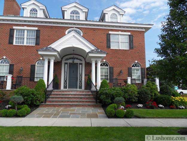 brick walls home with gray painted front door and beautiful landscaping